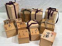 Group view of all ten wooden boxes showing variety in size, ribbon colors, and Japanese writing on lids.