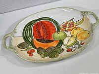 Full view of the large ceramic serving platter showing hand-painted fruit design and integrated handles