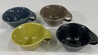Four Mid Century Modern style coffee cups in different muted colors (blue, brown, olive green, black) arranged together to show the set.