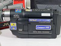 Side view of the JVC GR-AXM230 camcorder showing various feature stickers and lens with 400x digital zoom.