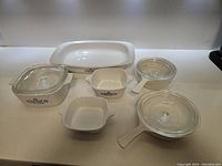 View of 9-piece CorningWare bakeware set including rectangular and square baking dishes with blue cornflower design, some with clear glass lids.