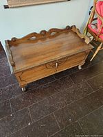 Front and top view of antique solid oak blanket chest with carved wood backboard, key lock, and cabriole legs on casters.