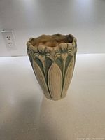 Front side of the 1940s McCoy pottery vase showing detailed embossed floral design with green and beige colors, scalloped rim visible.