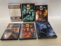 Six Babylon 5 DVD cases arranged in two rows of three on white surface.