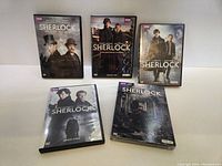 Five DVD cases for Sherlock including four seasons and The Abominable Bride special. Arranged lying flat on a white surface.