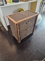 Front angle view showing the three wicker drawers with wooden frame and woven knobs