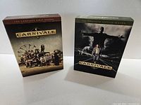 Photo showing Carnivale Complete First Season and Second Season DVD box sets side by side on a white surface with clear lighting, displaying cover art and box condition.