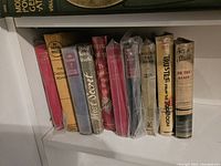 Photo of 10 hardcover Nevil Shute books with varied dust jackets on a shelf.