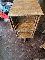 Solid wood library bookcase angled with view of vertical slats and adjustable shelves on central spindle.