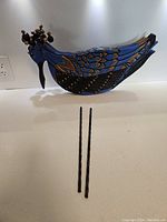 Wooden blue painted peacock planter with rebar legs on a white countertop.