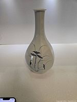 Front view of vintage Asian ceramic vase showing chrysanthemum floral design in blue on white background, slim neck and rounded body.