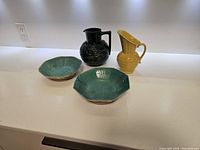 4 vintage pottery pieces displayed on white countertop showing two bowls and two pitchers