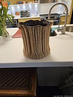 View of the ceramic planter from the side showing the ribbed, textured exterior and scalloped rim.