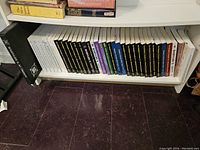 Shelf with a row of 36 Babylon 5 books including scripts, commentaries, and limited editions, showing clean condition and organized layout.
