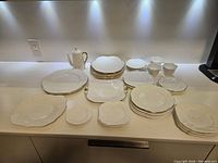Overall view: coffee pot, stacked plates, bowls and small dishes on countertop