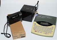 Four electronic items on surface: Sony alarm clock radio, Brother label printer, Polaroid Color 600 camera with wrist strap, and Wacom One cable box visible underneath.