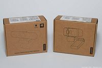Two Lenovo webcams in original brown packaging with line-art images of the webcams on front and Lenovo branding.