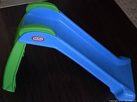 Blue and green plastic toddler slide assembled and standing, showing slide surface with Little Tikes logo.