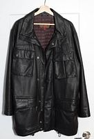Front view of black leather jacket showing four flap pockets, snap buttons, and drawstring hem.