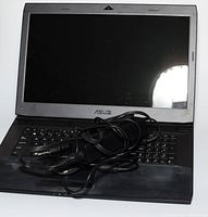 Open laptop with screen and keyboard visible, power adapter placed on keyboard.