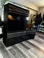 Front view of the black lacquered bedroom dresser showing the doors and drawers with rounded top detail and metal handles.