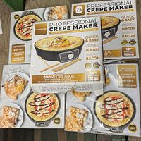 Top view of five boxed 12-inch professional crepe makers stacked together showing branding, features, and crepe images on packaging.