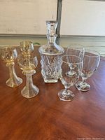 View of the full crystal glassware set including decanter and six glasses on a wooden surface with light background.