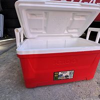 Red Igloo cooler with white lid open, showing interior and side handles.