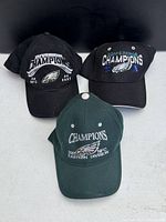 Three Philadelphia Eagles hats from front showing embroidered championship details