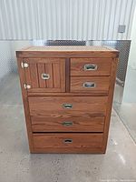 Front view of the dresser showing four large drawers, two small drawers above, and one cabinet door on the left side with metal handles.