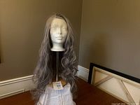 Wig displayed on a mannequin head showing length and wave texture with grey synthetic hair.