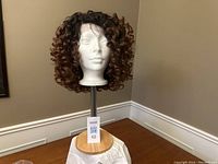 Front view of reddish brown curly lace frontal wig displayed on mannequin head stand.