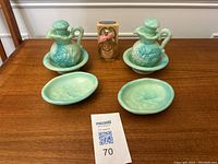 Two green Avon Jadelite perfume bottles with matching saucers and soap dishes, plus the boxed California Perfume Anniversary Keepsake bottle on a wooden table.