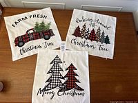 Photo showing all three Christmas-themed cushion covers arranged on a wooden table.
