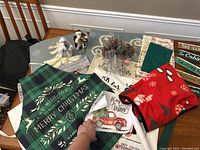 Photo showing entire lot of Christmas home decor including apron, Santas, cushion cover, blanket, floral arrangements, ski lodge sign, and canvas prints.