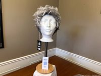 Full view of grey and white short synthetic wig displayed on mannequin head stand showing side profile and layered haircut.