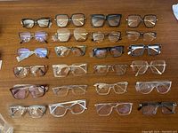 Photo showing 27 optical frames arranged in rows on a wooden surface.