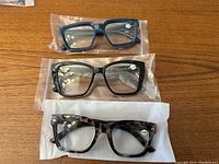 Three pairs of reader glasses laid out showing different frame colors and strengths.