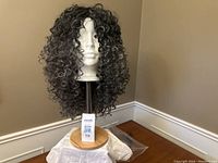 Front view of a curly salt and pepper grey synthetic wig on a mannequin head showing length and texture of hair.