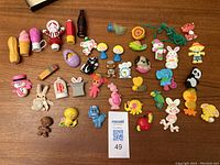 Overview photo showing all 39 vintage Avon children's perfume pins and lipsticks laid out on a wooden surface, displaying various animal and character shapes.