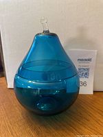 Pear shaped aqua blue glass artwork dish with lid on, displaying the deep blue color and smooth contours.