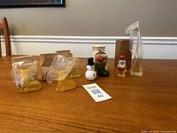 Seven vintage Avon cologne figure bottles displayed on a wooden table, including snowman, stocking, Santa, giraffe, and four sitting bear bottles.