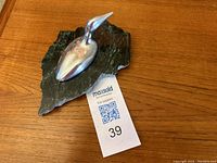 Front perspective showing aluminum loon sculpture and green marbled base on wooden surface with MaxSold tag