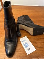 Front and angled side view of black leather ankle boot showing pointed toe, stiletto heel and zipper closure.