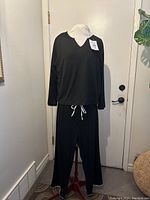 Front view of women's black lounge suit on dress form showing long sleeve top and matching pants with white drawstrings and piping