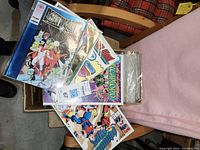 Box filled with many comic books with visible titles including X-Men and Avengers.