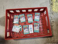 Multiple Coca-Cola collectible cards featuring polar bear illustrations inside a red plastic crate-style case on a concrete floor.