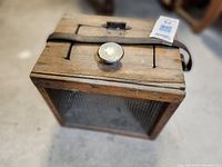 Top angled view of the wooden box showing metal mesh front, metal knob, latch, and leather handle.