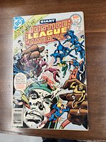 Front cover of Justice League of America comic issue 144 showing various superheroes and story highlights.