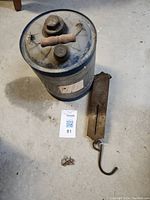 Overall view of cylindrical metal tin, metal scale weights and metal counterweight with hook